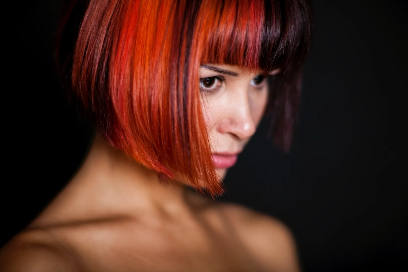 person with fiery red to blonde ombre hair against dark background