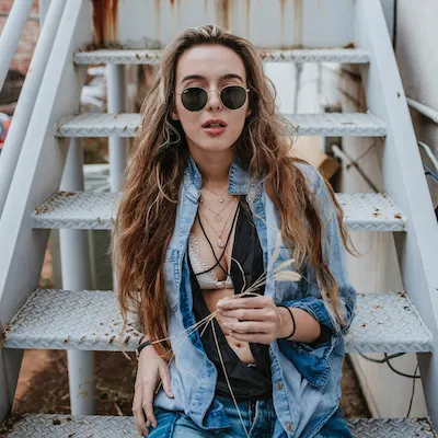 woman in sunglasses sitting on metal stairs